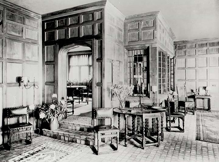 ornate chairs and tables on a tile floor, with oriental carpets, leaded glass and coffered wood panelled walls